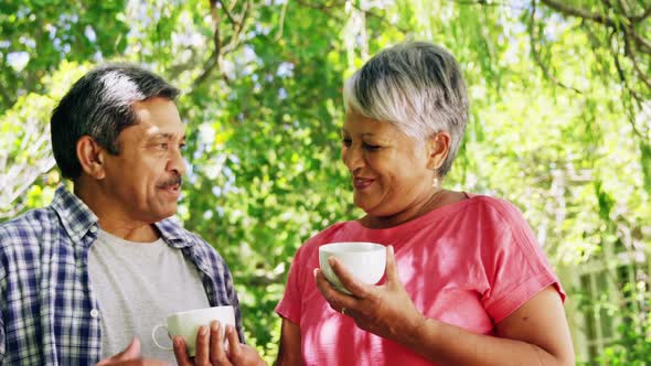 Senior couple interacting while having coffee in park