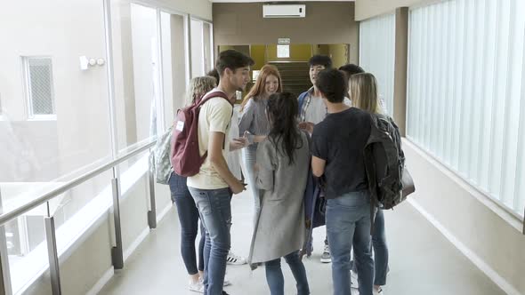 Group of students taking selfie with smartphone in corridor