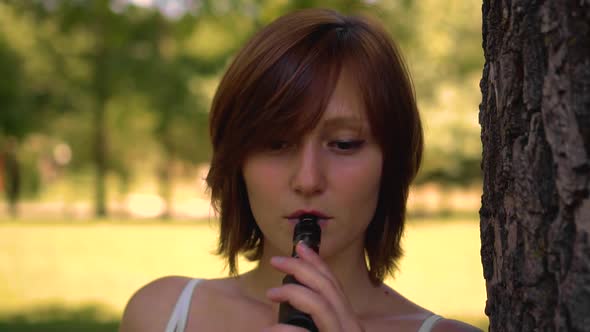 Young Girl Smokes Vape in the Park