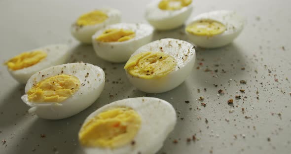 Video of close up of peppered halves of hard boiled eggs on grey background