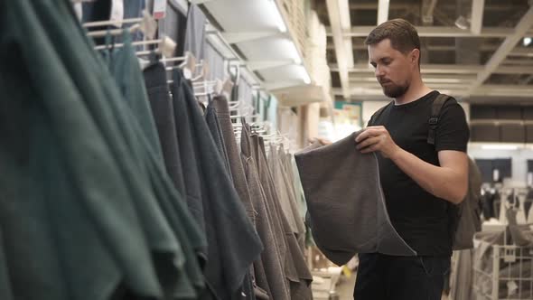 Man is Feeling Towel in a Shop Checking Softness in a Trading Area