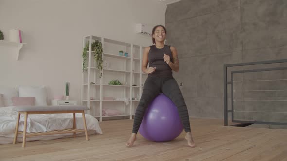 Happy African Woman Exercising on Fitball Indoors