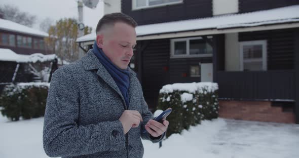 A Man Walks Down A Snowy Street, Dials A Number And Talks On His Cell Phone