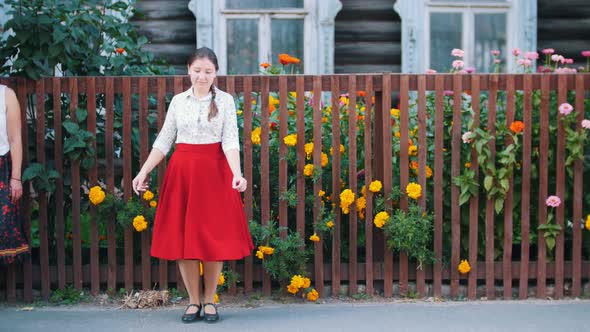 A Young Woman in Long Red Skirt Dancing By the Fence on the Street