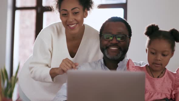 Laughing family talking by video call on laptop