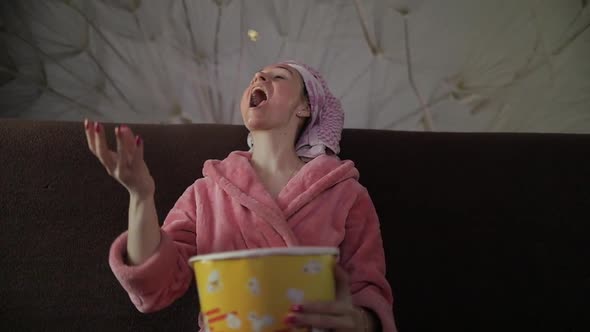 Woman Watching a Late Night Movie at TV, Eating Popcorn. Bathrobe, Facial Mask