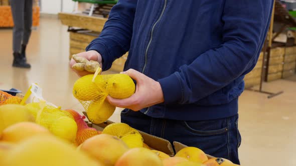 A Man Holds Lemons and Ginger in His Hands Buying Lemon and Ginger in a Store a Man Chooses