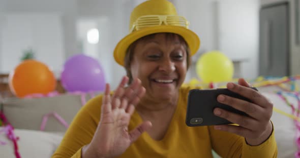 Happy african american senior woman making new year's eve smartphone video call blowing kisses