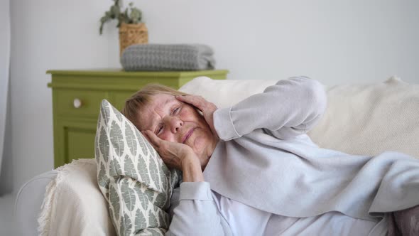 Old Sick Grandmother Resting On Sofa Suffering From Headache