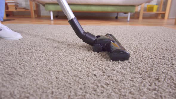 Young Woman Using Vacuum Cleaner While Cleaning Carpet in House Close Up