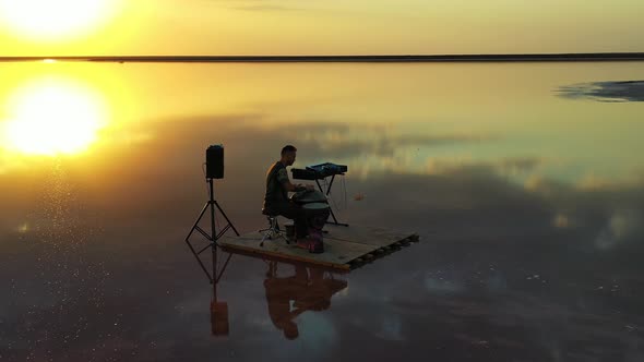 Aerial View on a Man on a Small Raft Playing Hang Drum, Reflections of the Sky