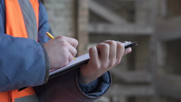 A civil engineer makes notes at the construction site of a high-rise building.