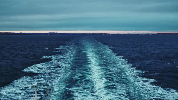 Wake In Sea Left By Ferry Leaving Coastline At Dusk