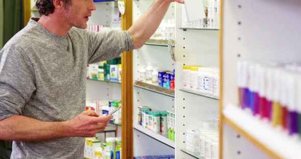 Customer using mobile phone with a bottle of drug in hand