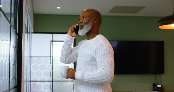 Senior man having coffee while talking on mobile phone