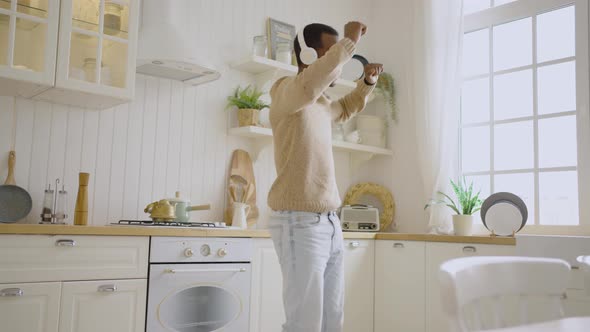 Happy African Black Man Dancing with Headphones at Home in the Kitchen