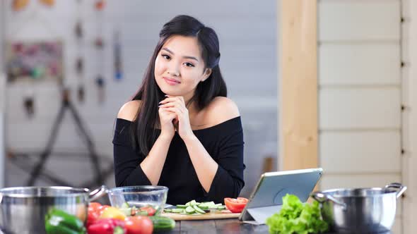 Portrait of Adorable Young Asian Girl Smiling and Posing Looking at Camera in Kitchen