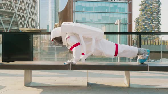 Astronaut doing push ups on bench in city