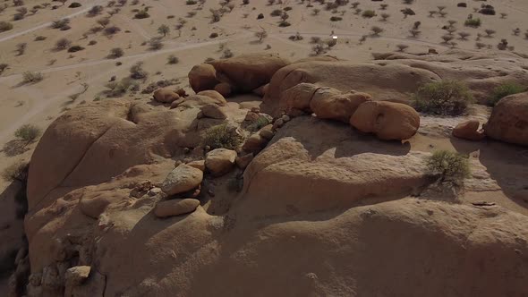 Drone is lowering behind a massive rock in the Namibian desert, amazing view