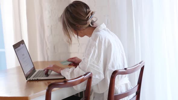 Woman in white shirt sitting in a table with laptop computer