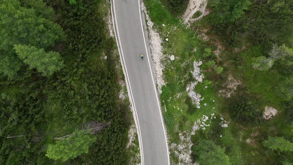 Flying above motorbikers and cyclists riding down a winding mountain road in the Dolomites