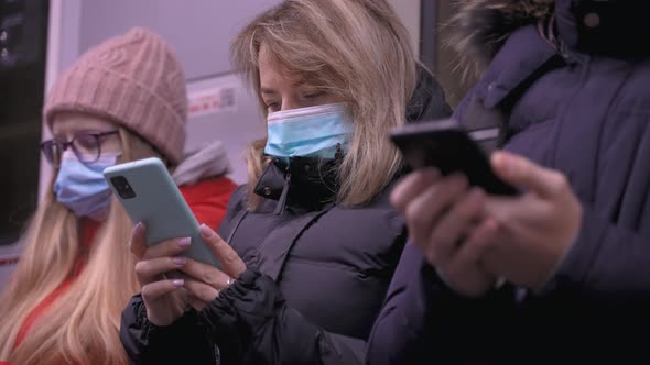 Masked Passengers Staring at Phones in Metro Train