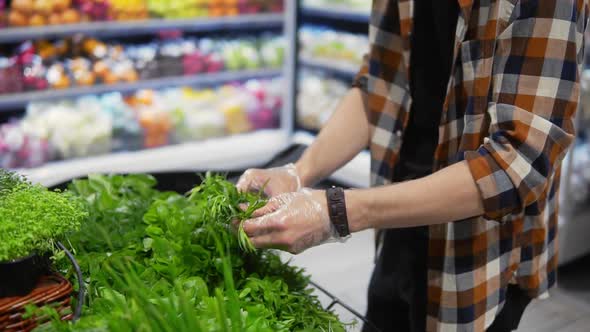 Young Man with a Protective Black Mask Walking in a Supermarket and Take Greens From the Shelf