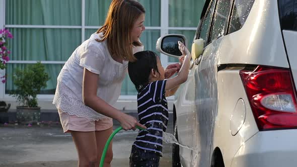 Asian Mother And Son Washing Car Together On Summer Day