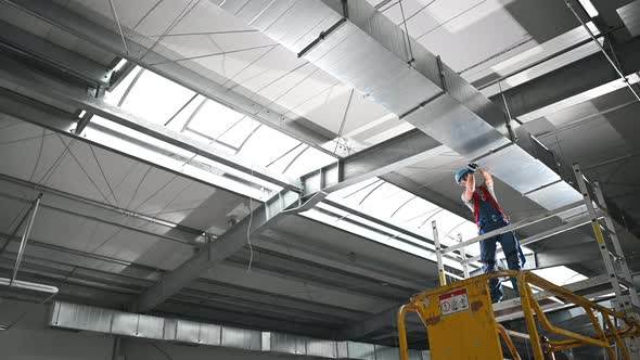 Caucasian Construction Male Worker Installing Industrial Air Ventilation