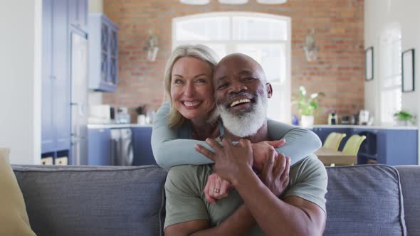 Portrait of mixed race senior couple hugging each other and smiling at home