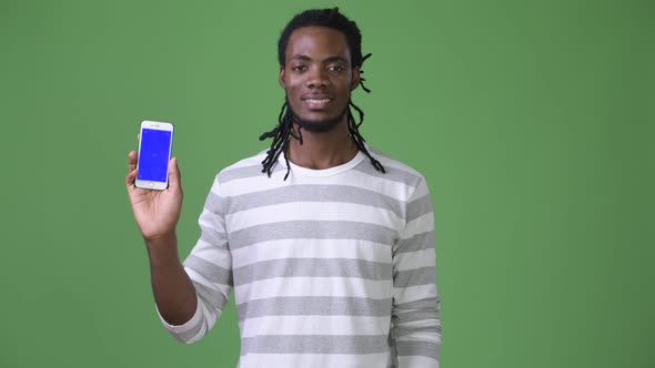 Young Handsome African Man with Dreadlocks Against Green Background