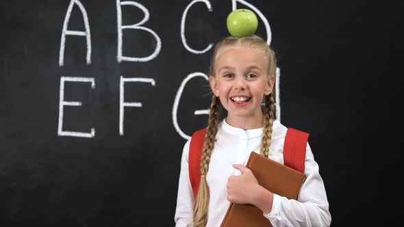 Pretty Schoolgirl Standing Near Blackboard With Apple on Head, Brilliant Idea