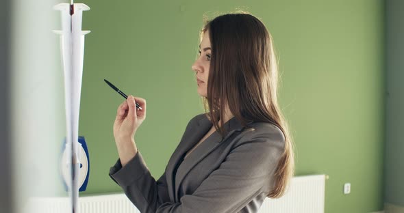 Beautiful Young Business Woman Performs Financial Calculations on Presentation Whiteboard. Working