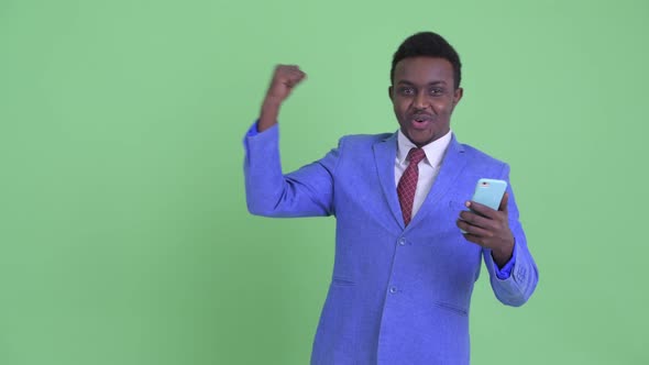 Happy Young African Businessman Using Phone and Getting Good News