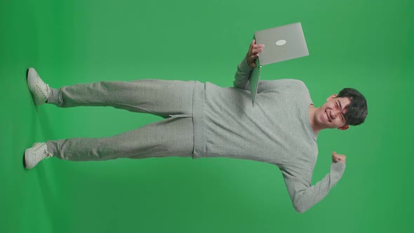 Full Body Of Smiling Asian Man Flex Muscle While Typing On Computer In The Green Screen Studio