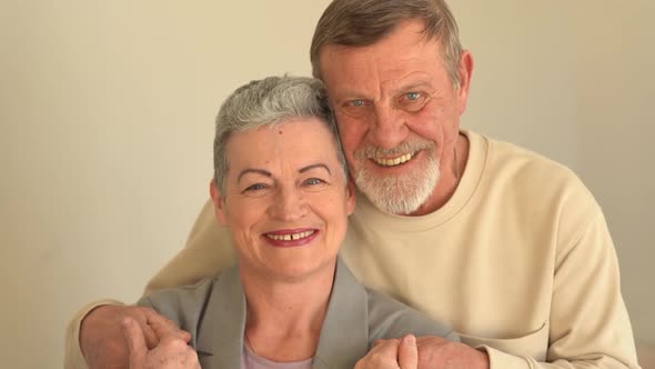 Close Portrait of Smiling Elderly Husband and Wife Looking at Camera