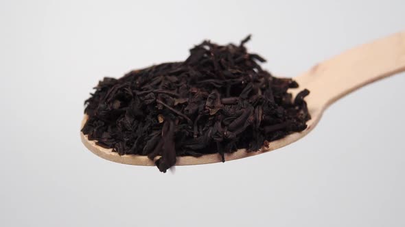 Wooden spoon full of dried black tea leaves