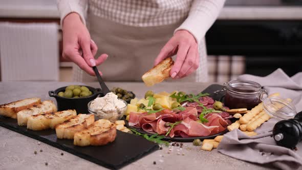 Making Bruschetta  Woman Smearing Cream Cheese on a Grilled Baguette