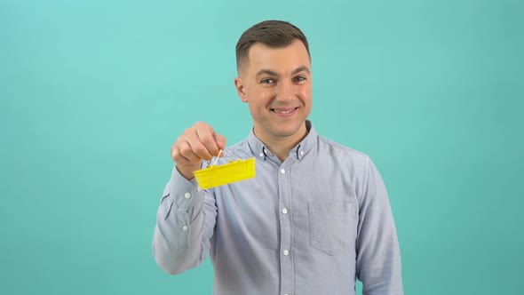 A Happy Positive Caucasian Man in a Blue Shirt Happily Displays a Toy Shopping Basket in His Hands