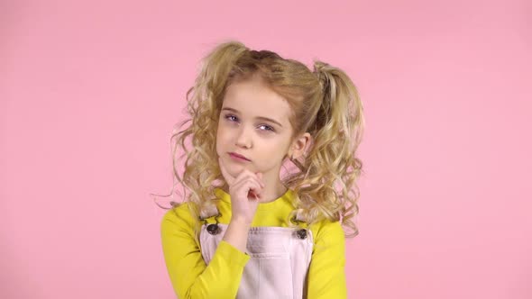 Blond Female with Two Ponytails Is Concentrated on Thinking, Touching Her Face with Finger. Slow