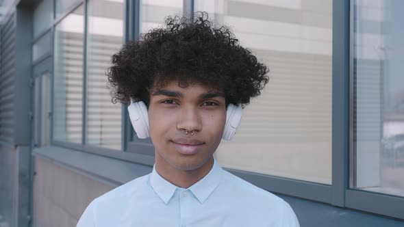 Caucasian Happy Beautiful African American Male in Headphones and Listening to Music Outdoors