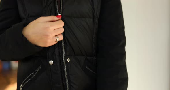 Woman's hand unfasten the zipper on a black jacket