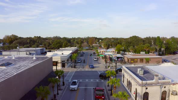 Slow Forward Aerial Pan of Cars Driving By Shops and Restaurants on a Main Road