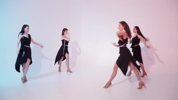 A Group of Four Girls in Elegant Black Dresses are Dancing in the Studio