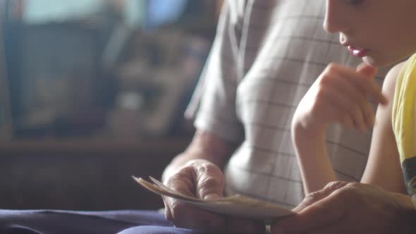 the grandson asks his grandfather about the family tree while looking at family photos while sitting