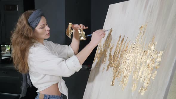 Young Female Artist Applying Gold Leaf to Her Artwork