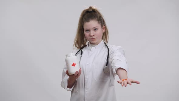 Positive Caucasian Girl Holding Pills Jar Stretching Hand with Orange Drugs Smiling Looking at