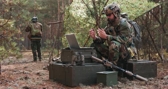 A Bearded Commander in a Military Uniform in a Tactical Vest with a Helmet on His Head Chatting