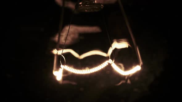 Tungsten Filament in a Glass Lamp Closeup in Slow Motion on Black Background