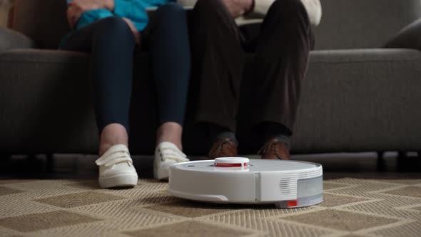Robotic Vacuum Cleaning While Old Couple Relaxing